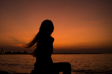 Silhouette of Asia Beautiful girl in quiet nature. There is an orange sunset in the background,copy space