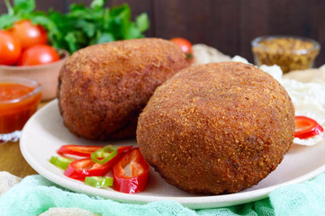 Juicy golden cutlets stuffed with boiled egg on a wooden background.