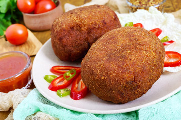 Juicy golden cutlets stuffed with boiled egg on a wooden background.