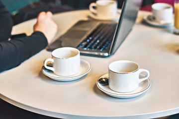 Busy morning with a laptop and many empty coffee or tea cups on the table