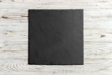 slate board on wooden background, space for writing text