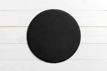 Black slate round stone on wooden background, top view, copy space