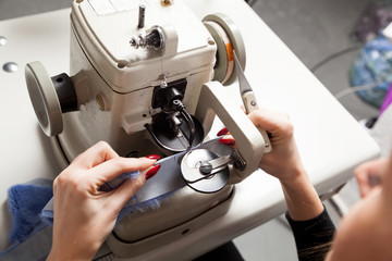 Woman scinner, furrier works on sewing machine with natural fur
