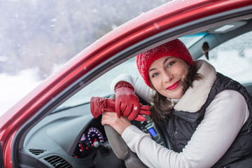 Girl in a red cap and warm jacket in a red car in a winter