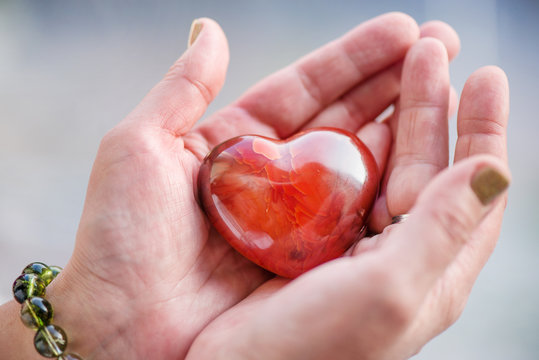 Mothers love. Woman's hands holding heart shaped gemstone. Healthy lifestyle concept - taking care of heart health. Healing crystals with powerful energy.