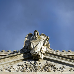 Obraz premium A statue of an angel placed above the temple. Sculpture was on top of a gravestone from the 1800's. The photo was taken in Cemetery of Bologna, Italy