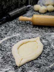 close up view of raw dough for traditional georgian khachapuri and wooden rolling pin on tabletop