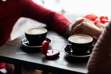couple in love holding hands, drinking coffee and sharing gifts at the café. man is making a proposal. valentine`s day concept