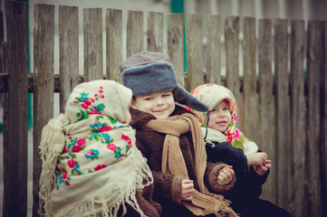 Obraz premium Village children are sitting on the bench under the house and eat seeds