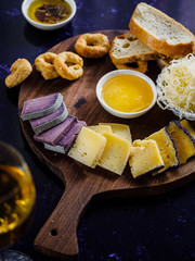 close up view of assorted cheese types, sauce and bread on wooden cutting board