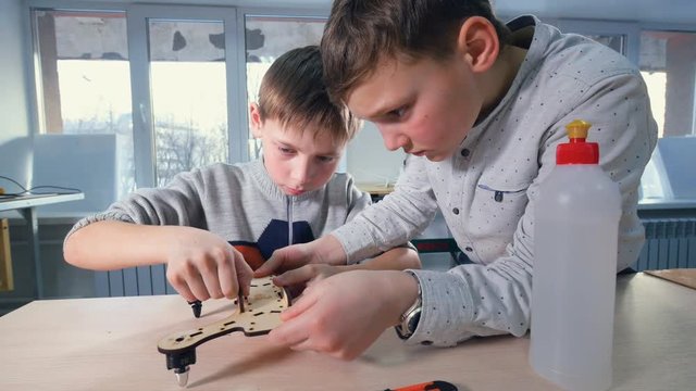 Two boys young engineers making drone model. 4K.