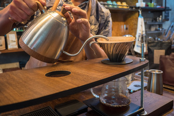 Hand drip coffee. Barista pouring water from silver teapot