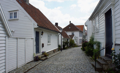 Narrow empty street with traditional white wooden houses in Gamle Stavanger in Rogaland, Norway, sunny day