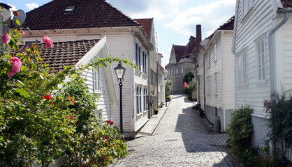 Fototapeta na wymiar Street with traditional white wooden houses in Gamle Stavanger in Rogaland, Norway, sunny day