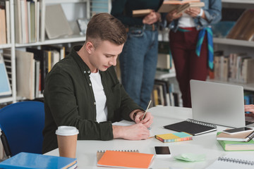 student writing something to notebook in library