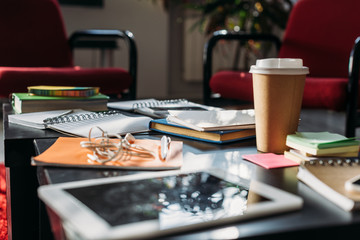 Naklejka na ściany i meble tablet with disposable coffee cup and notebooks on table