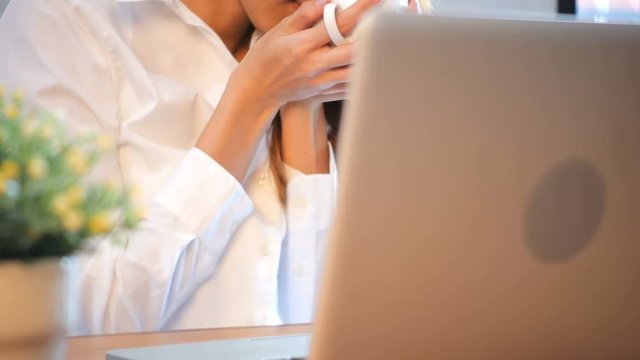 Young business women drinking coffee sitting at table in cafe. Asian woman using laptop and cup of coffee. Freelancer working in coffee shop. Working outside office lifestyle.