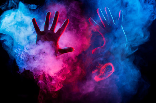hands inside colorful smoke on black background