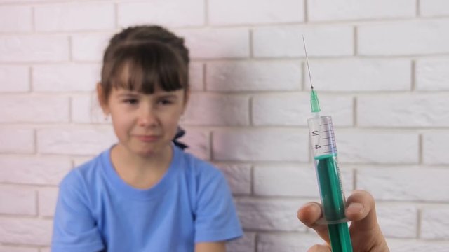 A child is afraid of a syringe. Fear of a syringe. Tears of a little girl.