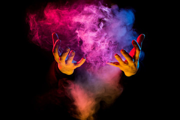 hands from colorful smoke on black background