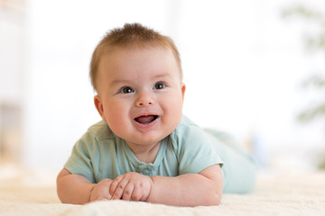 cute happy caucasian baby boy lies smiling on bed
