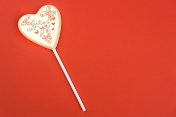 Chocolate lollipop with the inscription Love you, red background with a lot of copy space