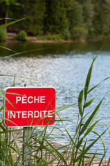"No fishing"- Sign prohibiting fishing at the edge of a lake in France.