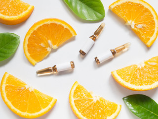 Vitamin C brown ampule for injection with fresh juicy orange fruit slices on white table. High dose vitamin c synthetic for white skin. Beauty product branding mock-up. Healthy lifestyle. Top view. - obrazy, fototapety, plakaty