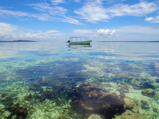 Boat over a shallow coral reef in calm water of the Caribbean sea