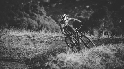 Wide angle view of a mountain biker speeding downhill on a mountain bike track in the woods