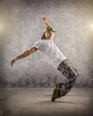 Naklejka na ściany i meble Hip Hop dancer in dynamic action jump on the grunge grey backgro
