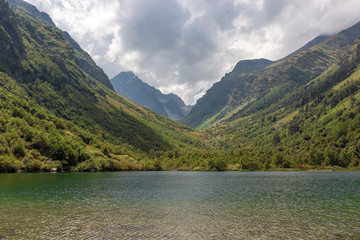 mountain gorge in summer, green trees and a lake in the Caucasus, Dombay with clouds in the sky