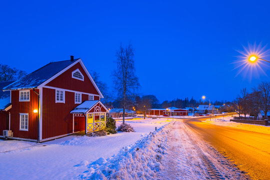 Winter scenery with red wooden house at night in Sweden