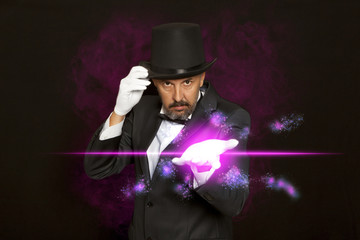 Magician in top hat showing trick on black