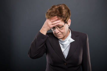 Business senior lady holding head like hurting