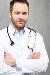 Uśmiechnięty młody lekarz
Przystojny lekarz ubrany w biały kitel stoi w klinice
 - obrazy, fototapety, plakaty