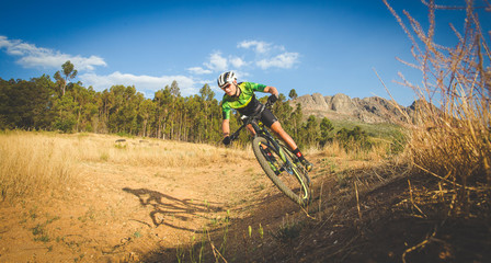 Wide angle view of a mountain biker speeding downhill on a mountain bike track in the woods