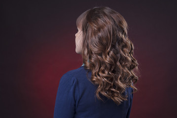 head brown-haired woman with curly hair on a dark red background isolated head turning to the left