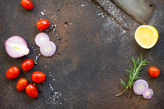 Culinary background with cherry tomatoes, onions, fresh rosemary and spices. Top view with a copy.