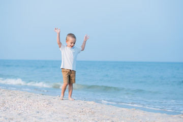 Summer vacation - Portrait of lovely boy walking on the beach near water