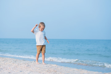 Summer vacation - Portrait of lovely boy walking on the beach near water