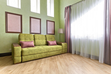 Интерьер в зеленых и розовых цветах с зеленым диваном и светлым паркетом