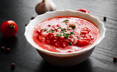 Traditional Italian tomato soup gazpacho in bowl on dark wooden background