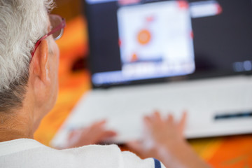 Old person in glasses busy working with a laptop