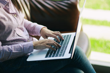 Naklejka premium Freelancing woman using laptop computer for distance job while sitting in coffee shop. Business woman typing on laptop at workplace Woman working in home office hand keyboard.