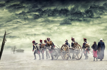 Napoleonic soldiers and women marching and pulling a cannon in plain land, countryside with stormy...