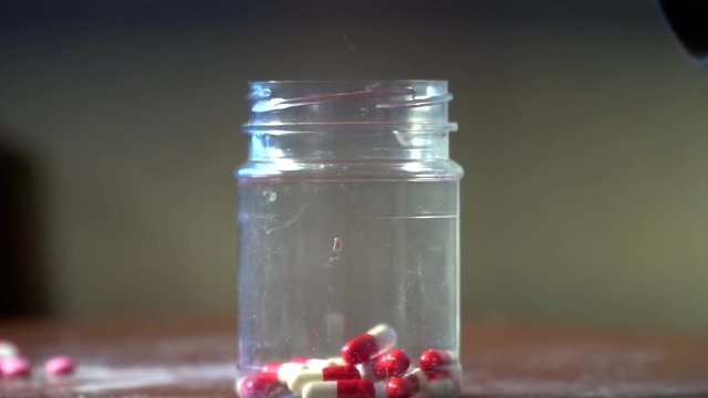 man pour into a jar of pills
