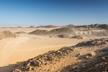 Traces of the car on the sand in the desert against the backdrop of the mountains.