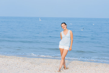 Happy woman on the beach. Portrait of the beautiful girl close-up, the wind fluttering hair. Spring portrait on the beach. Young pretty girl. Young smiling woman outdoors portrait. Close. ocean