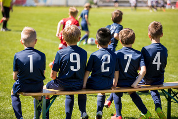 Kids sport team sitting on a bench. Group of kids soccer players. Children football club. Football...